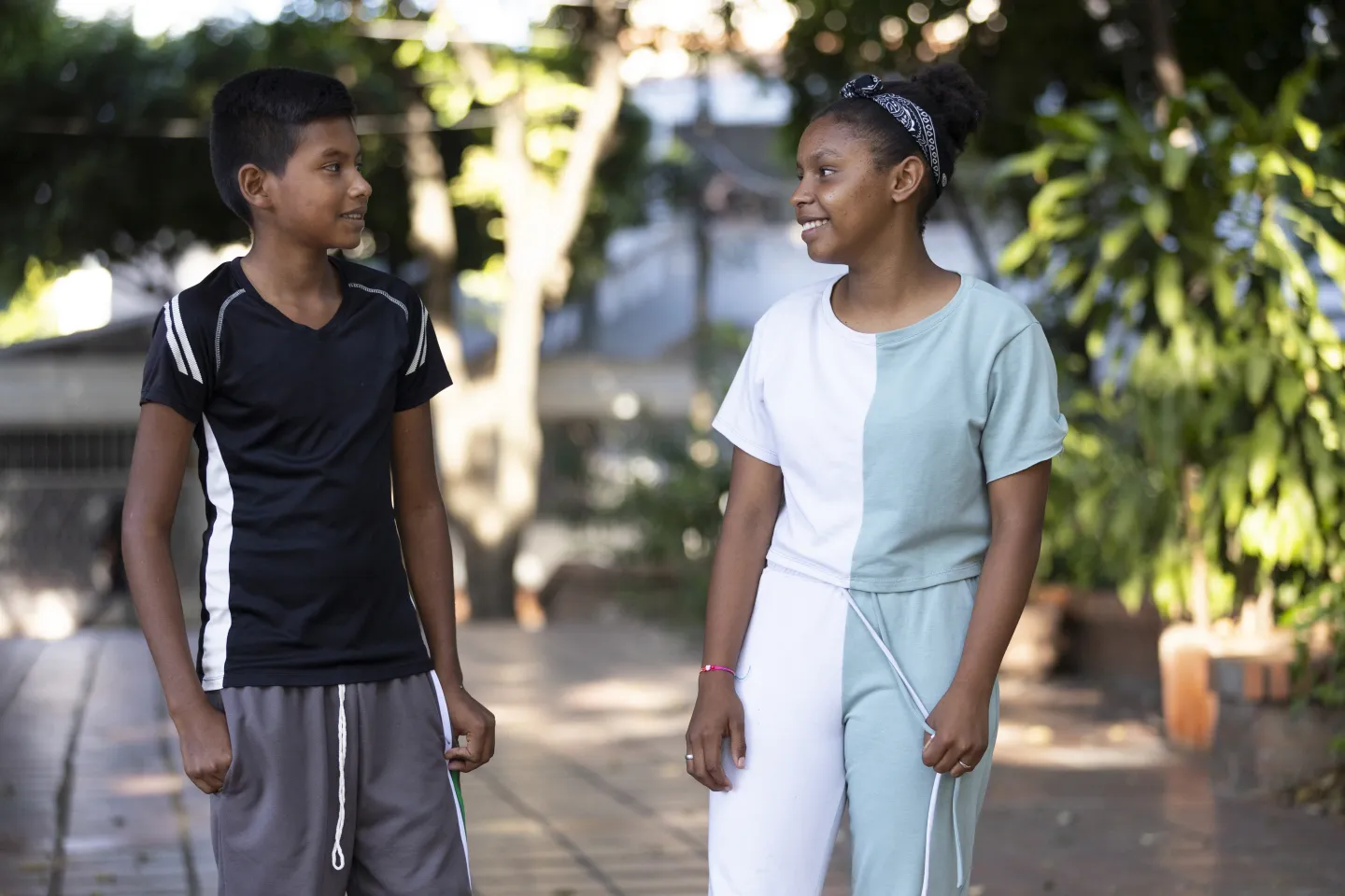 Teenagers Juan and Dairilys look at each other while they walk down a sidewalk