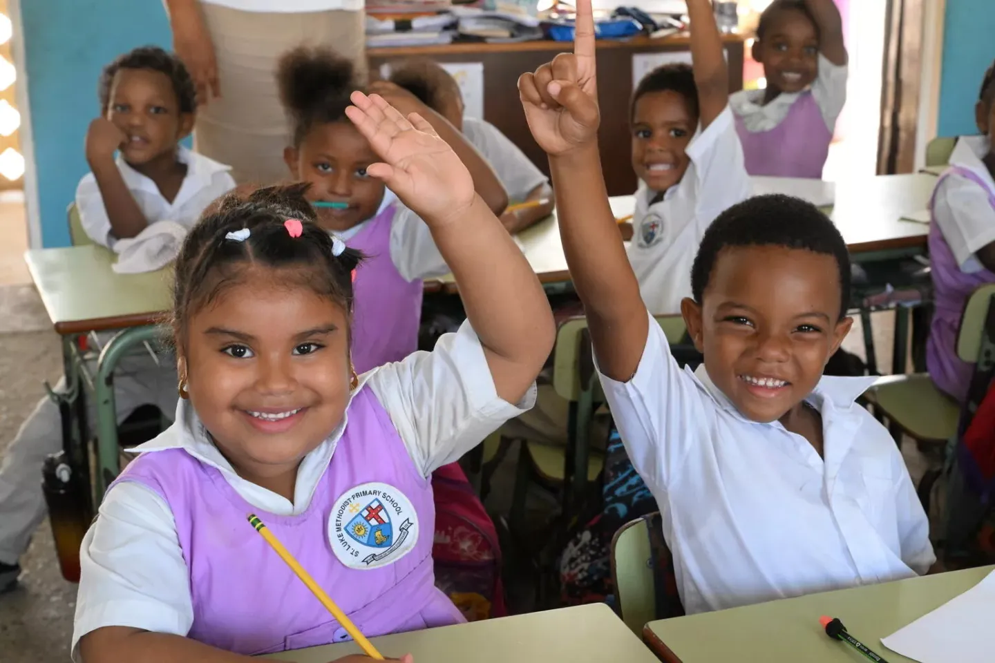 Un ni&ntilde;o y una ni&ntilde;a levantando la mano para participar en clase