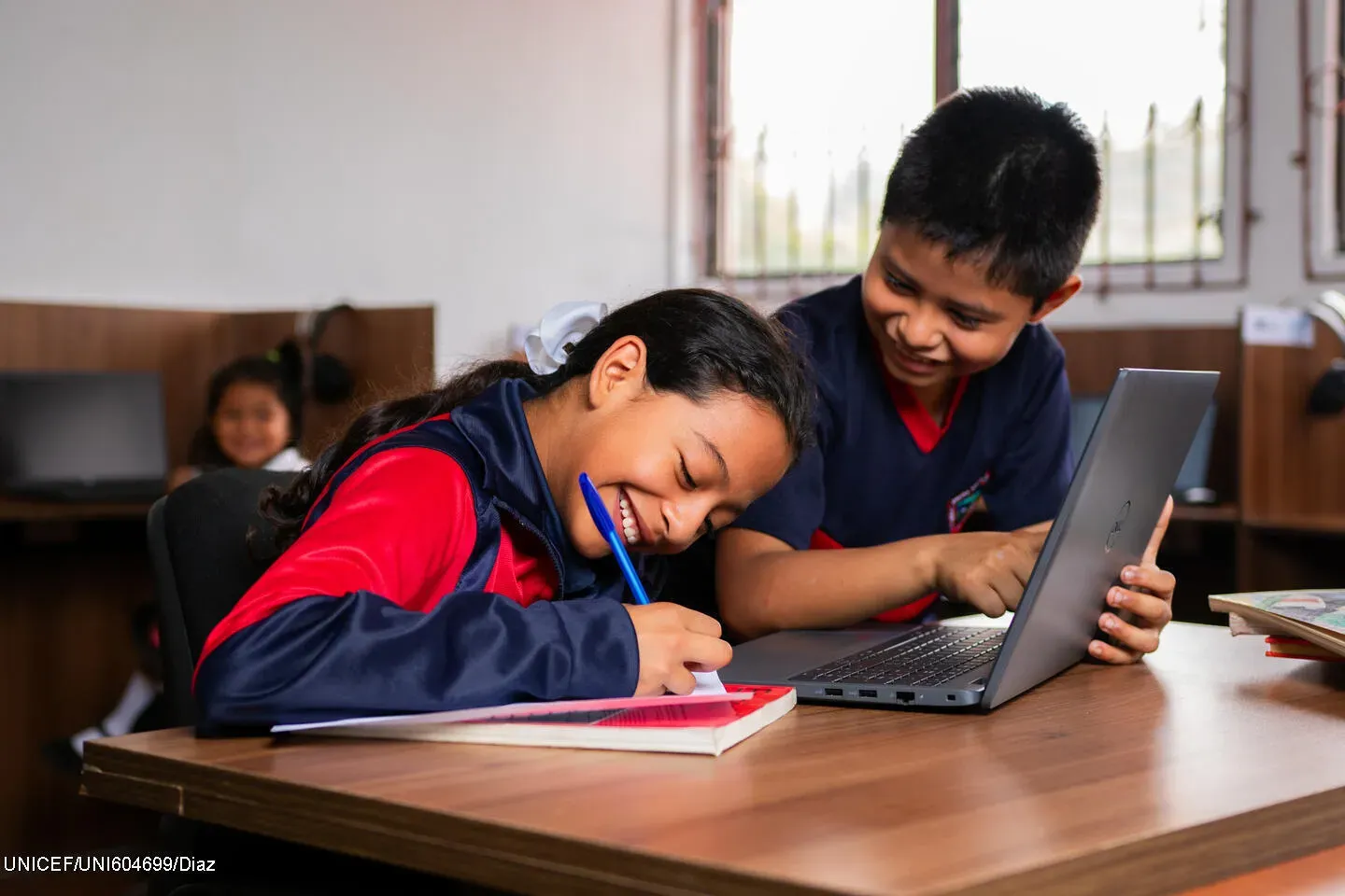ni&ntilde;o y ni&ntilde;a usando computadora y haciendo apuntes