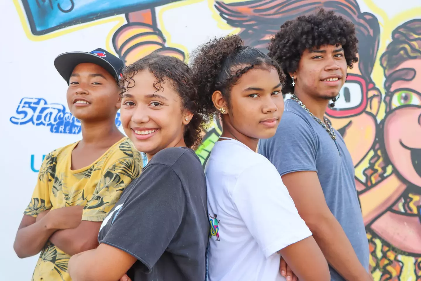 Adolescentes de pie sonriendo frente a un mural