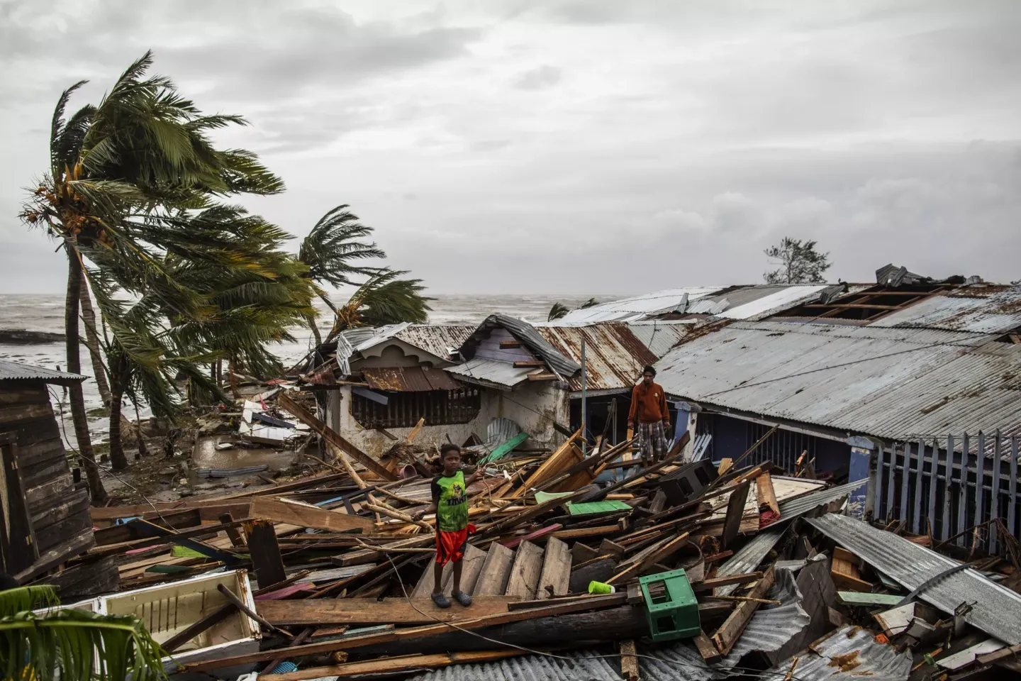 un ni&ntilde; de pie sobre una casa destruida por un huracan