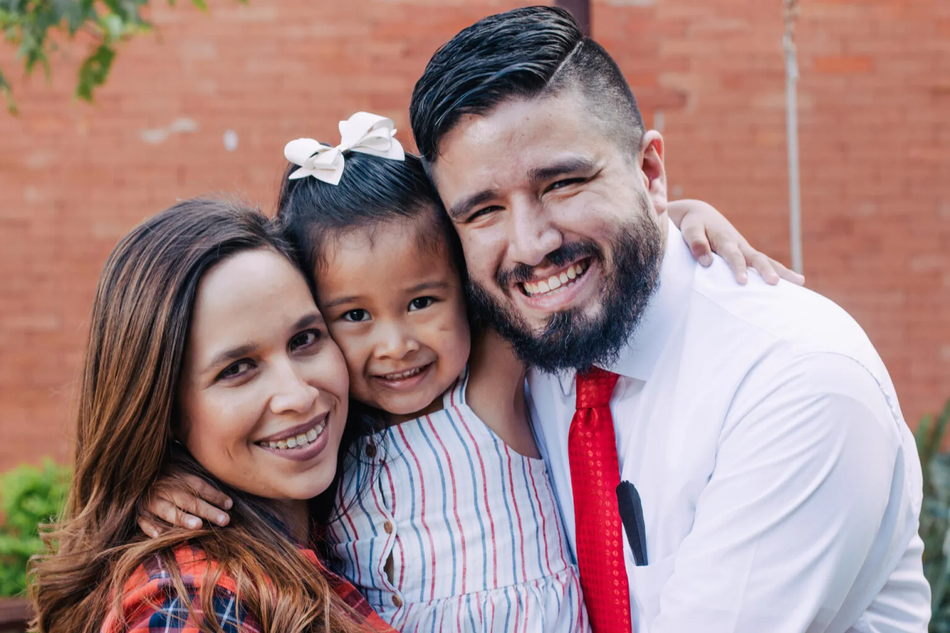 Pap&aacute;, mam&aacute; e hija sonriendo.