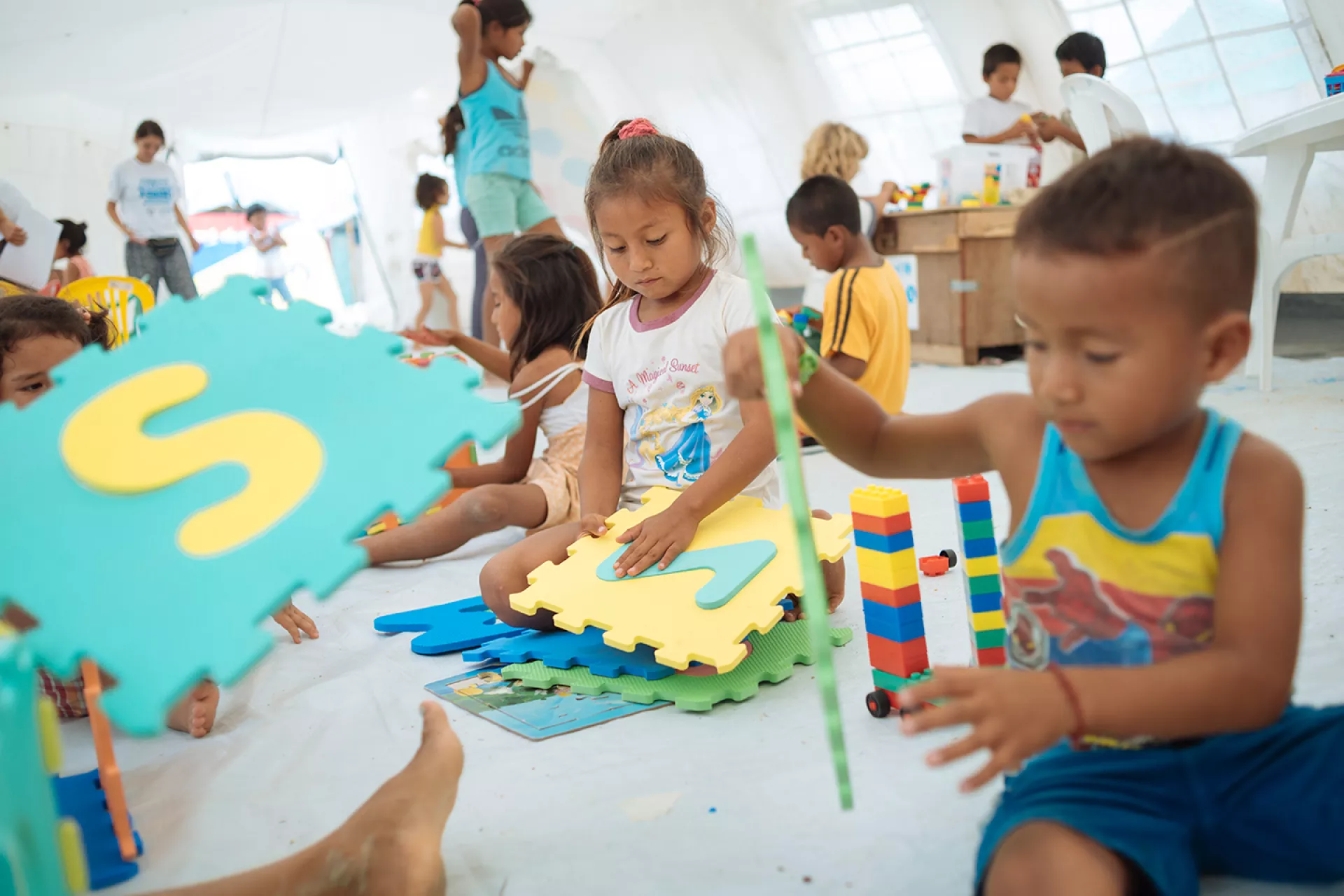 Ni&ntilde;os y ni&ntilde;as disfrutan de actividades l&uacute;dicas junto a miembros de Unicef en el Espacio Amigable para la Ni&ntilde;ez ubicado en el albergue Portete