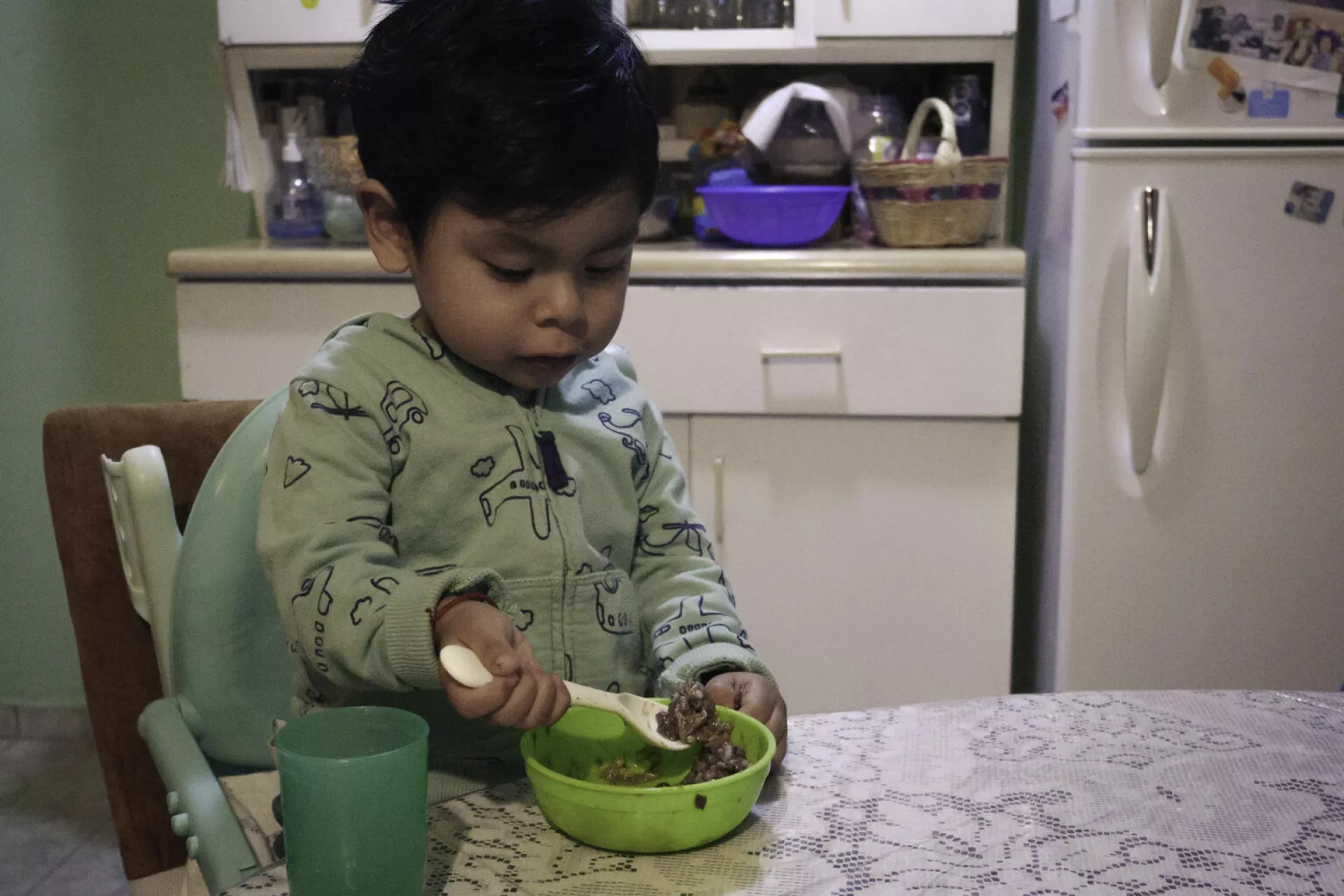 ni&ntilde;o peque&ntilde;o mirando su plato de comida con una cuchara en la mano