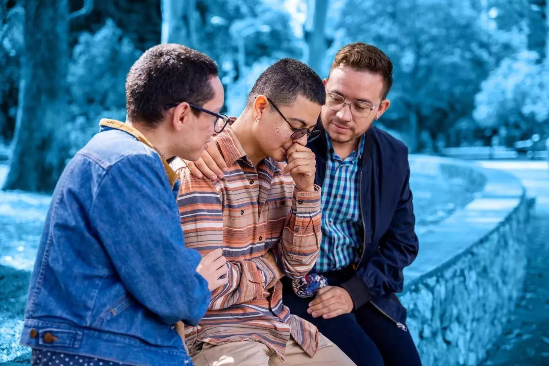 dos personas abrazando y brindando apoyo a un tercer amigo