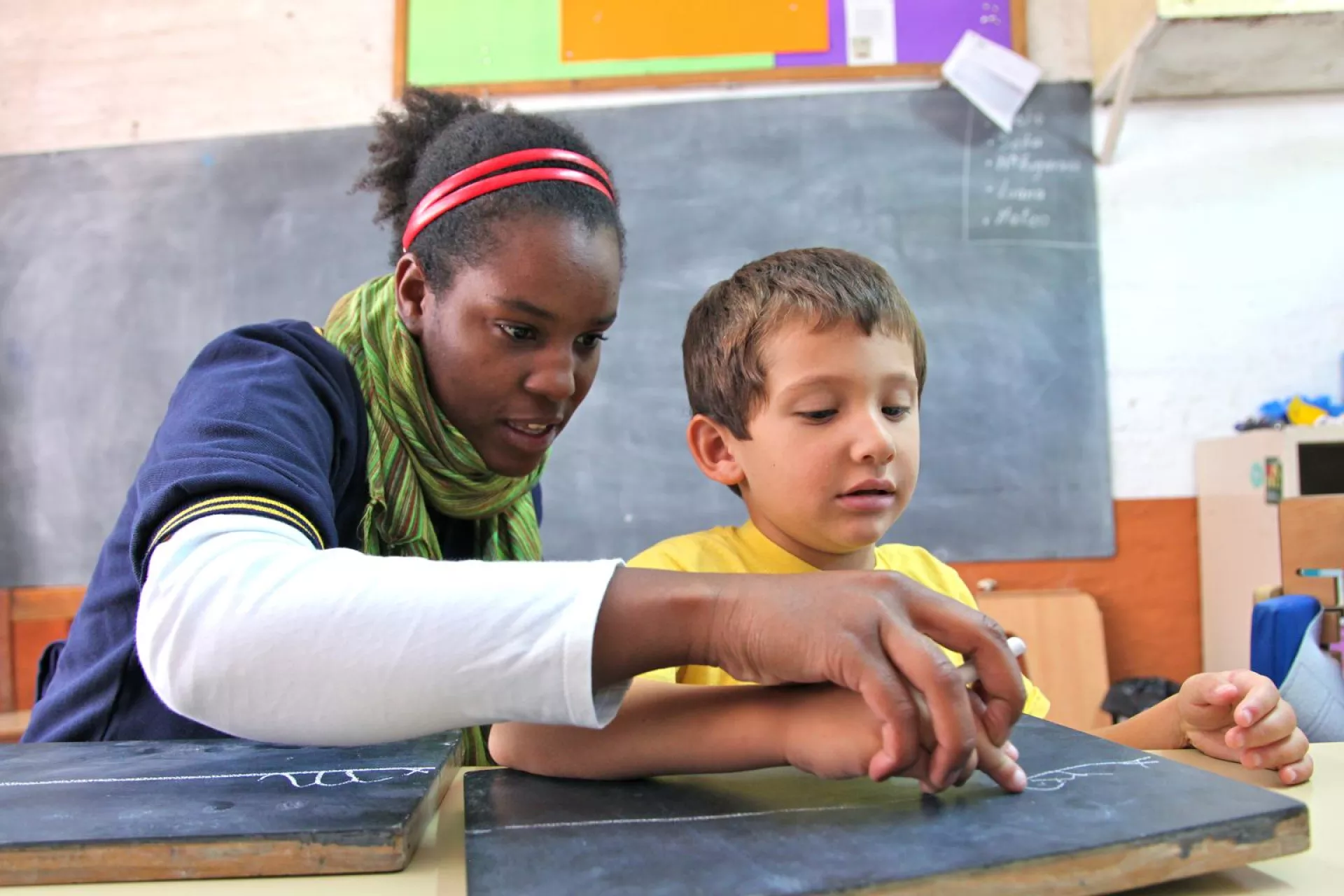 Leandro, 5, writes on a small chalkboard with the help of his teacher, Rosana, during a personalized learning session for children with disabilities at CENI, an inclusive school in Montevideo, the capital.
