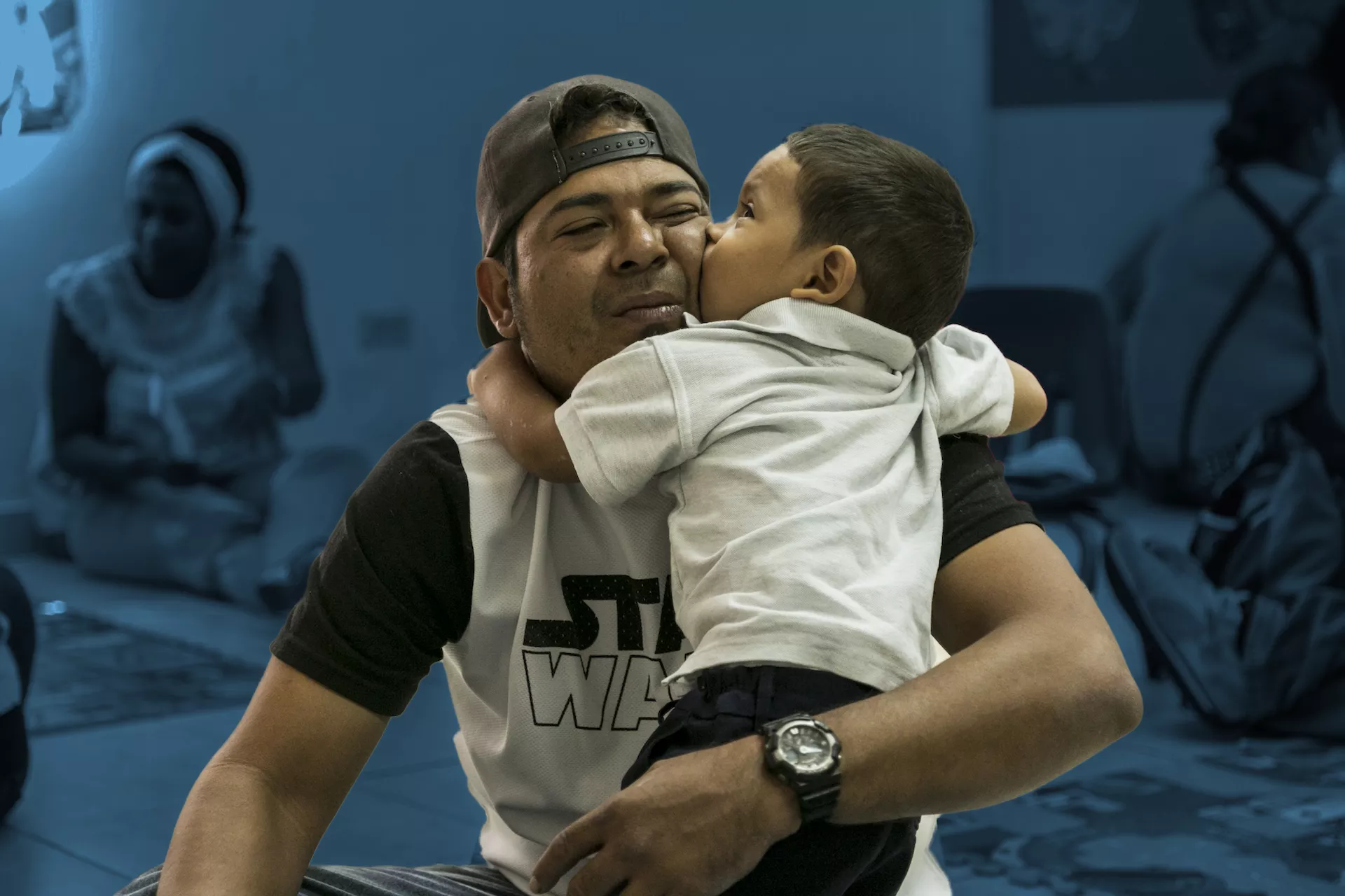 Young boy hugs and kisses his father at a Care for Child Development clinic