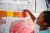 Una adolescente coloca una nota en una pared que contiene otras notas en papeles de diversos colores.