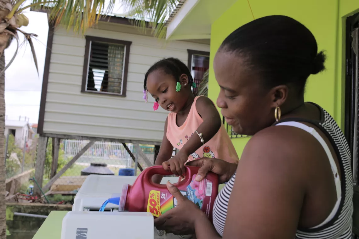 Alishia, de 3 a&ntilde;os, ayuda a su madre en el lavado de la ropa en su hogar, en Belize.