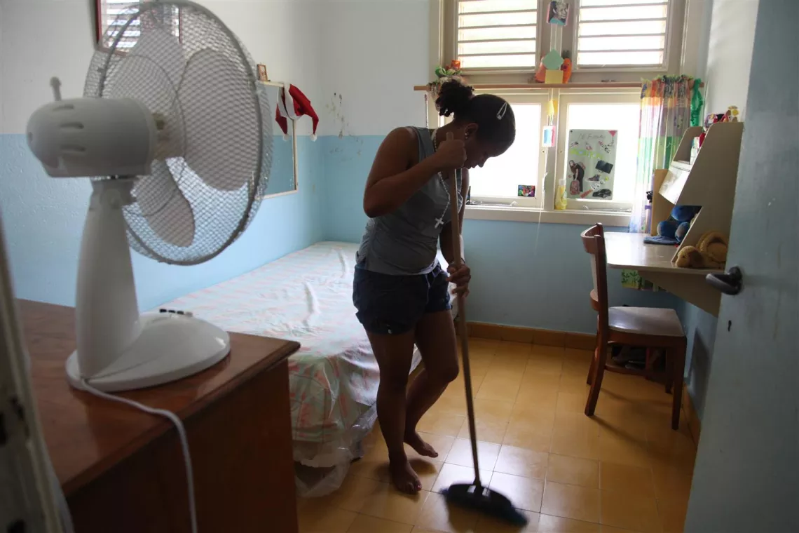 Una joven barriendo en el interior de su casa.
