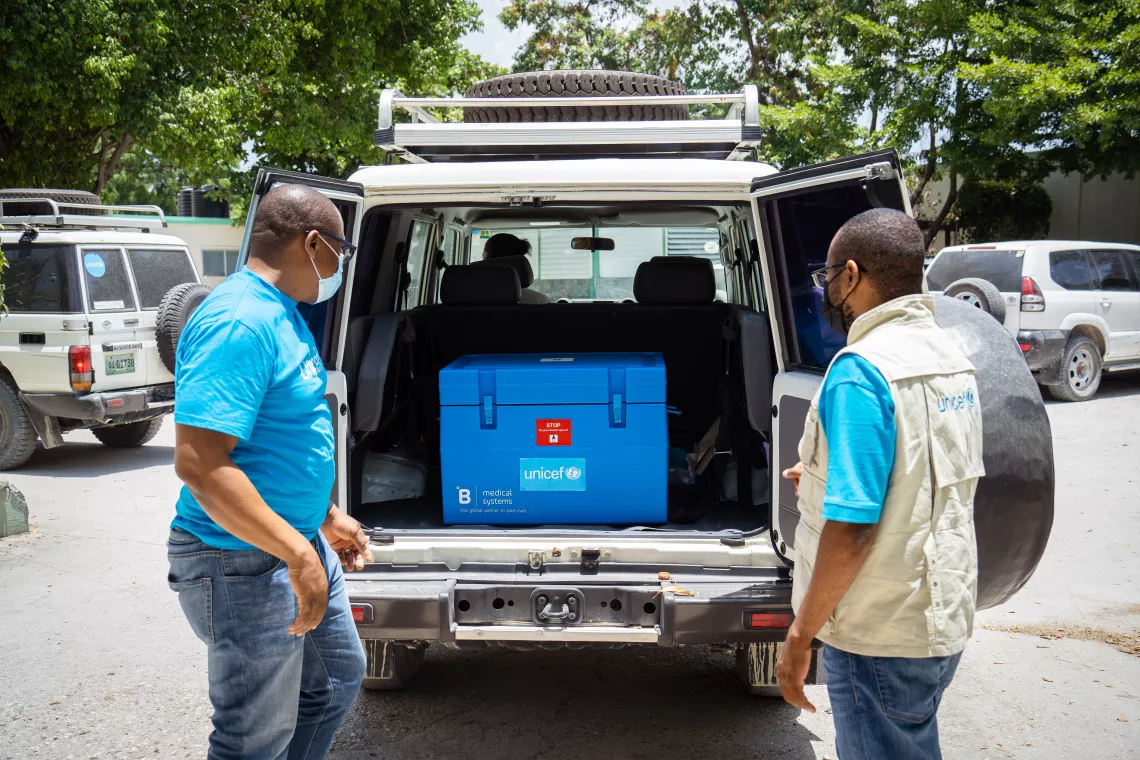 Ernsly Jackson, UNICEF Immunization Specialist, and Karl Marx Dossou, UNICEF Immunization manager transport COVID-19 vaccines to a UNICEF solar-powered fridge in l’hôpital Saint-Damien (also known as Petit-Frere et Sœurs)
