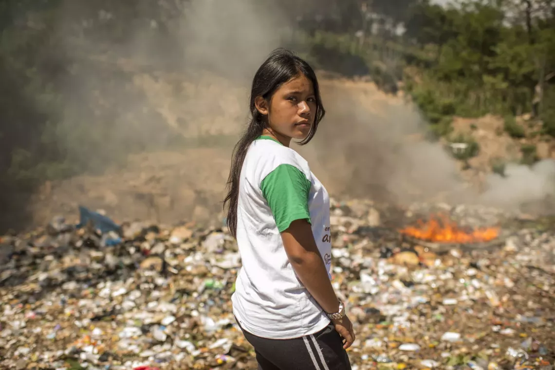 Activista en Guatemala frente a un lote donde se quema basura 