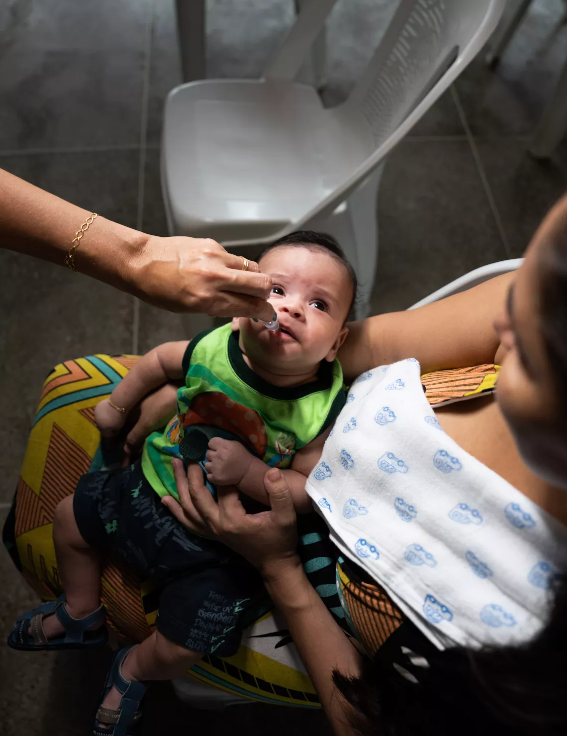 A vaccine is dropped into the mount of an infant boy.