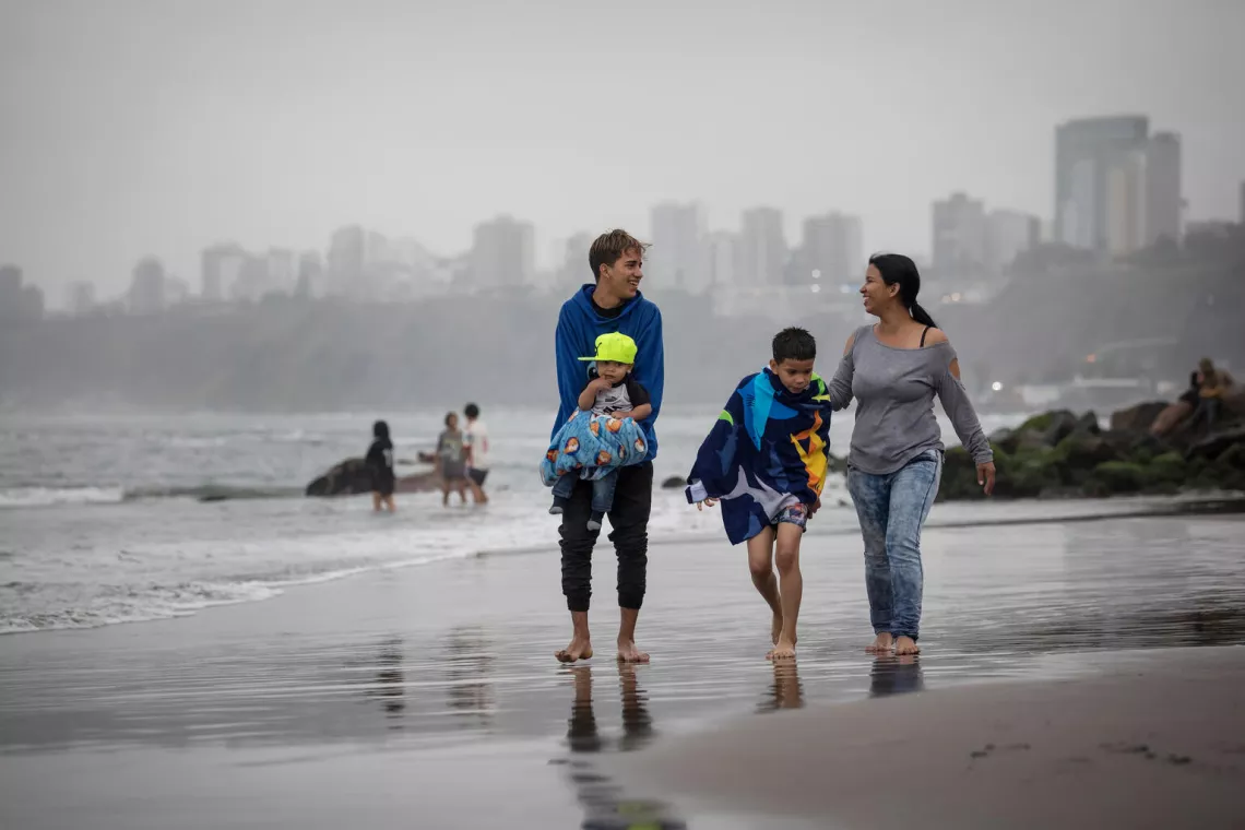 Rubén junto a sus dos hermanos menores y su mamá caminan en la playa Los Yuyos