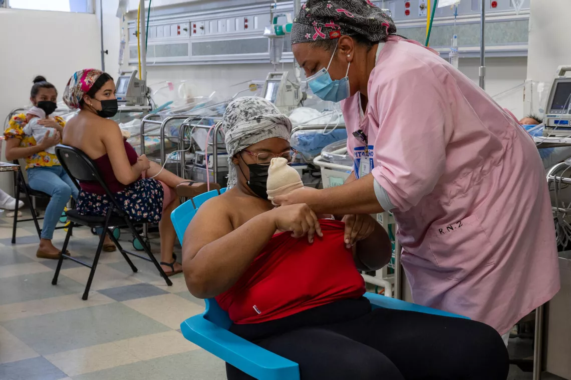 enfermera est&aacute; ayudando a una madrea a cargar a su bebe recien nacido en el pecho, plan canguro