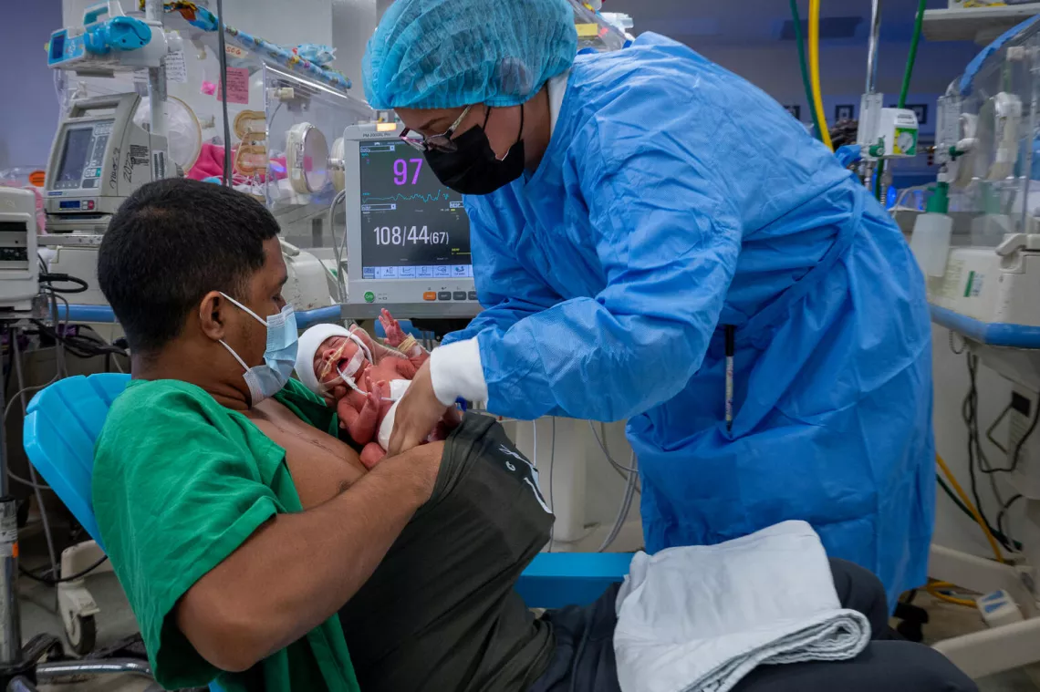 beb&eacute; recien nacida, apoyado en el pecho desnudo de su padre, plan canguro, en un hospital.