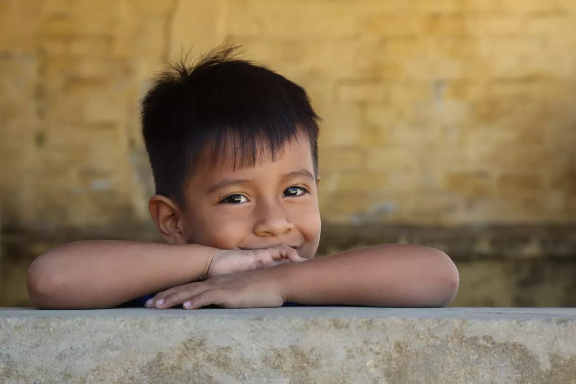 Un ni&ntilde;o apoyado sobre un muro, sonriendo