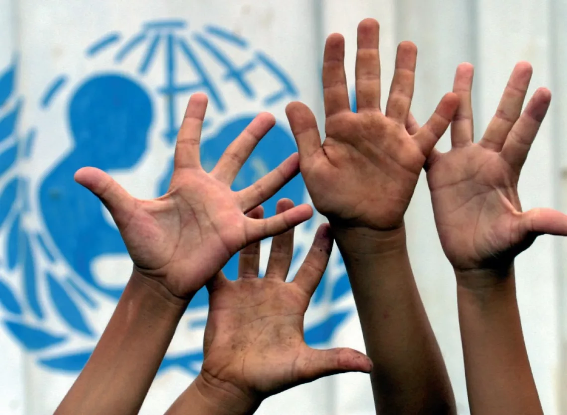 Manos levantadas de ni&ntilde;os frente al logo de UNICEF