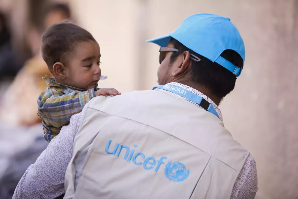 Un trabajador de UNICEF carga a un ni&ntilde;o peque&ntilde;o