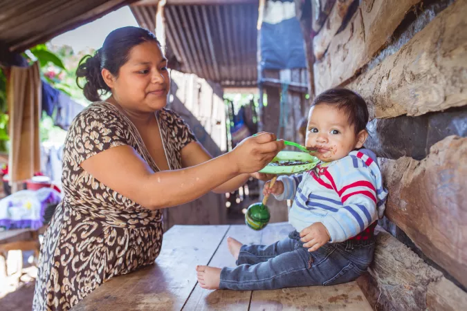 Una madre da de comer a su hijo de 8 meses de edad.