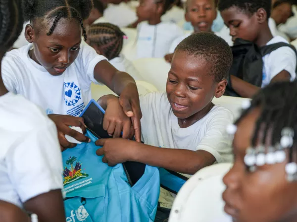 Un grupo de ni&ntilde;os y ni&ntilde;as recibiendo mochilas