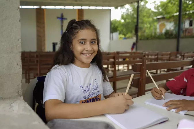 Una ni&ntilde;a sonriendo mientras sostiene un l&aacute;piz