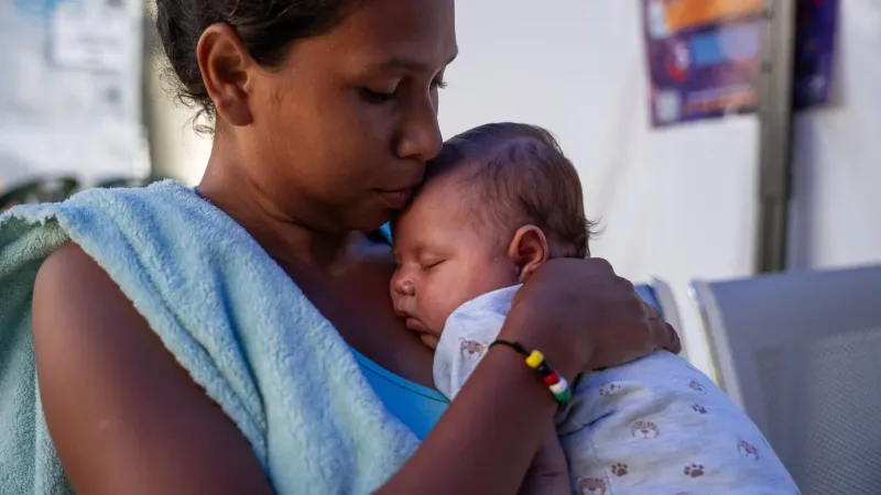 Una madre carga a su beb&eacute; en brazos mientras le da un beso