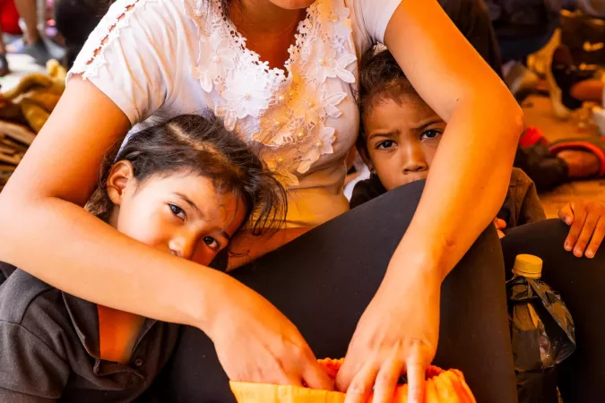 Dos ni&ntilde;as abrazadas por su madre