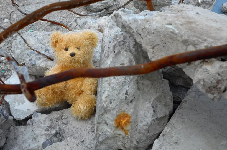 A teddy bear seated on rocks.