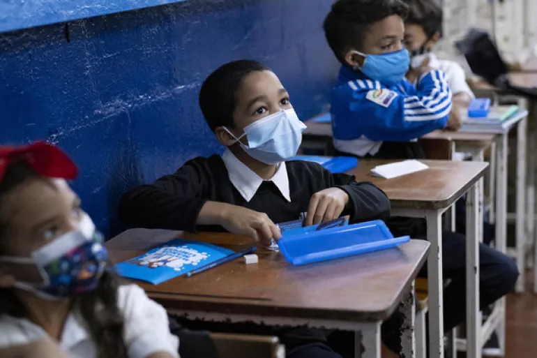 Children with masks in a classroom.