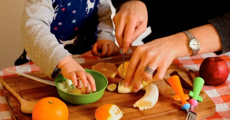 Madre, padre e hijos cortando alimentos.