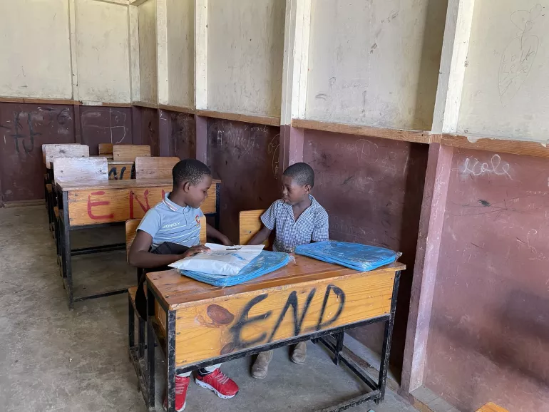 Two Haitian children seated in an empty classroom.
