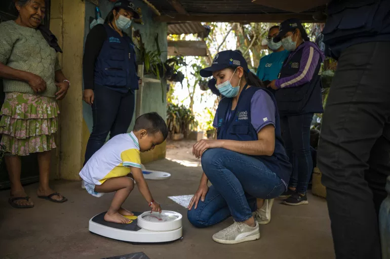 A child is weighed by UNICEF during a comprehensive immunization and nutrition outreach visit to Guatemala