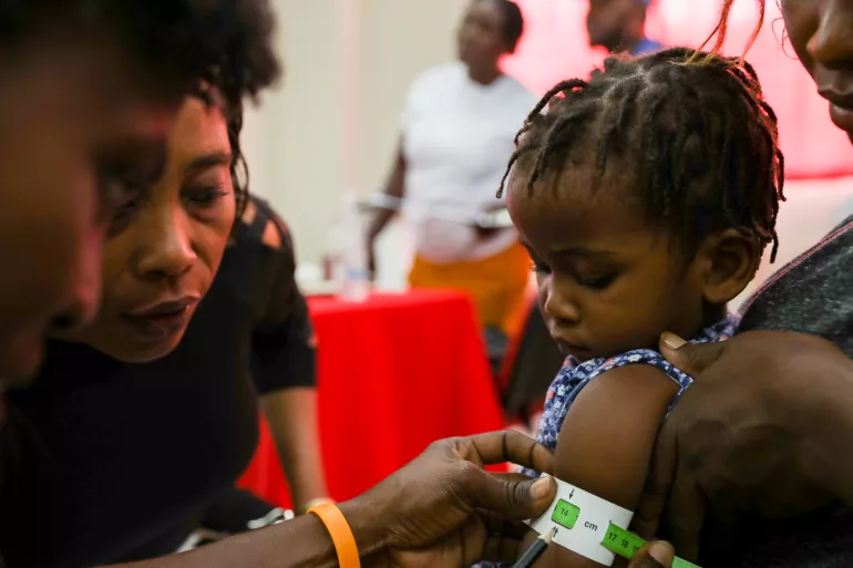 A multi-purpose community health worker measures the upper arm circumference of a daughter during a workshop before deployment to the field.