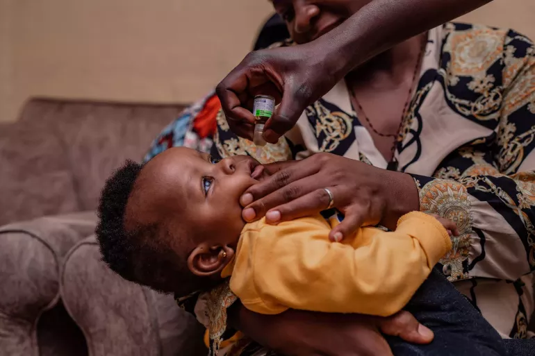 A woman holds a boy while he receives the vaccine against polio 