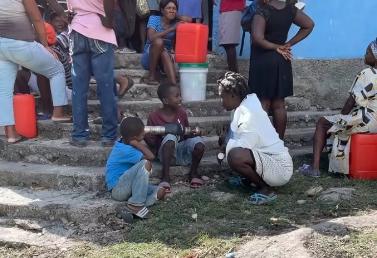 Dos ni&ntilde;os haitianos conversan con una vecina.