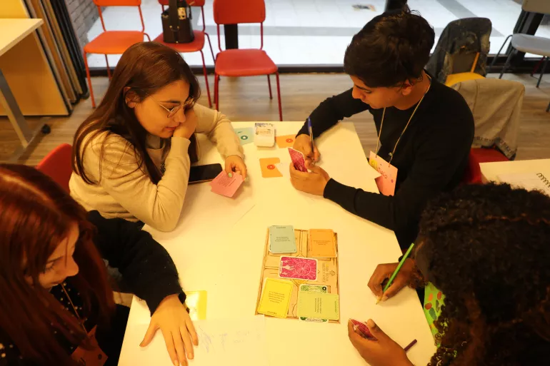 j&oacute;venes alrededor de una mesa jugando colectivamente, el juego de mesa de salud mental