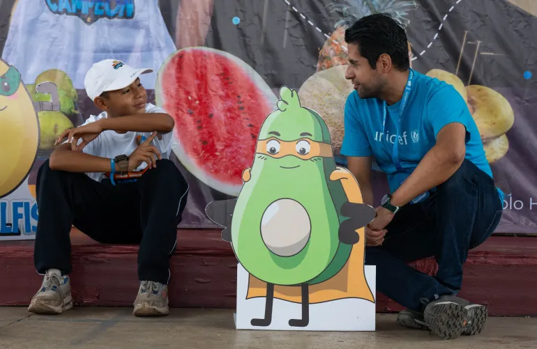 Un hombre  y un nino sentados junto a un carte de una palta o aguacate