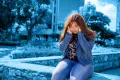 adolescentes sentada sola, tap&aacute;ndose los o&iacute;dos con ambas manos.