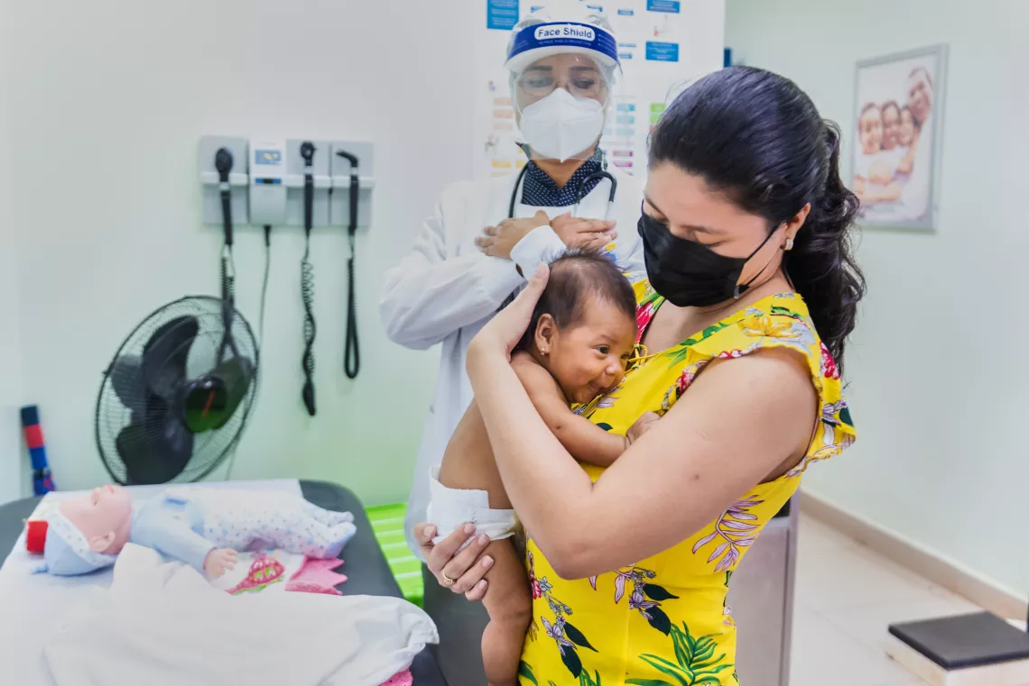 Una madre cargando a su beb&eacute; durante una visita rutinaria al pediatra.