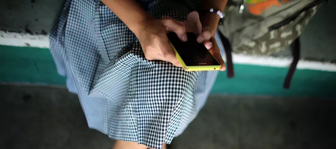 una adolescente sostiene un celular 