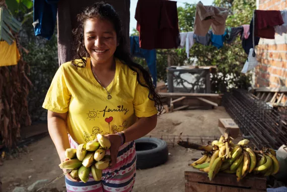 Mujer joven cargando unos pl&aacute;tanos