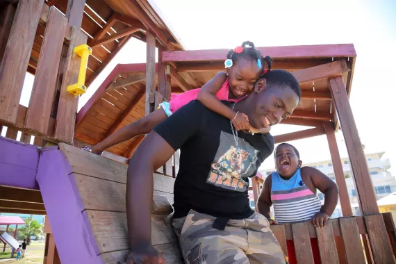 Alishia Gentle, 3, plays with her brother, 17-year-old Andrew, and her cousin, KJ, in a park by the water in Belize City