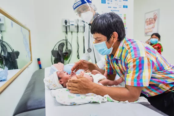 Ocu, Panama, June 2021. A father holds his baby during a routine check-up with the pediatrician. Doctor Cornelia Thomas counsels the famliy on Care for child Development (CCD), a program implemented by UNICEF in Latin America and the Caribbean.