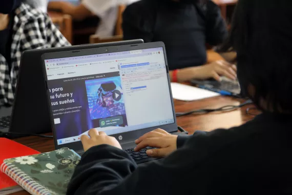 Un joven est&aacute; usando una computadora port&aacute;til 