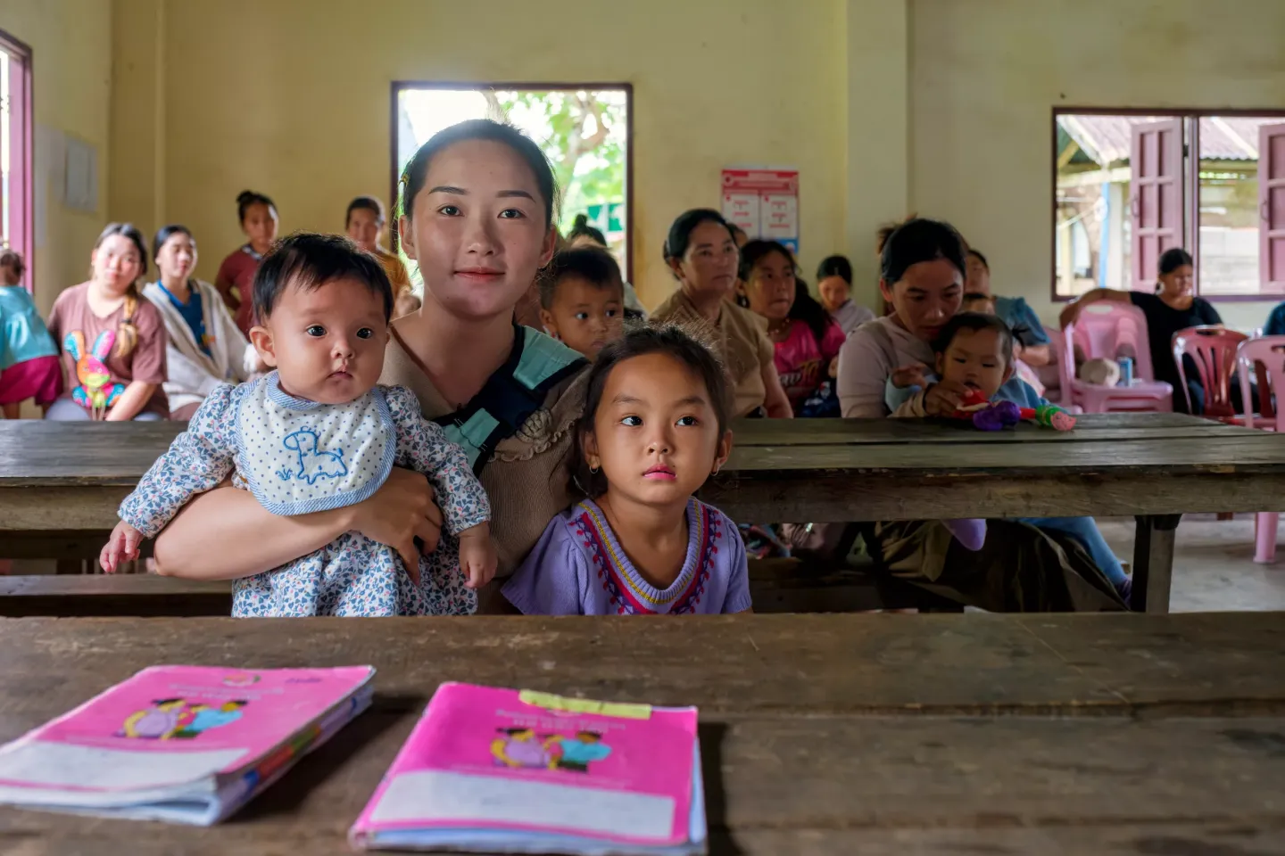 NAXOOM GOVERNING OFFICE, VANG VIENG DISTRICT, LAOS - NOVEMBER 5, 2024 &ndash; NOVEMBER 5 - Mrs. Suaheu (26) with her daughter, Yuanli (4 months), and two of her young sons from Nasom village, Vangvieng district, Vientiane province, speaks with &nbsp;Ms Chandavone Xayavong, Deputy head of Namuang Health Center, as Ms. Chandavone reviews the new green vaccination certificate book for vaccination record updates. Tablets are now also being used to register vaccination data. During the health consultation and nutrition edu