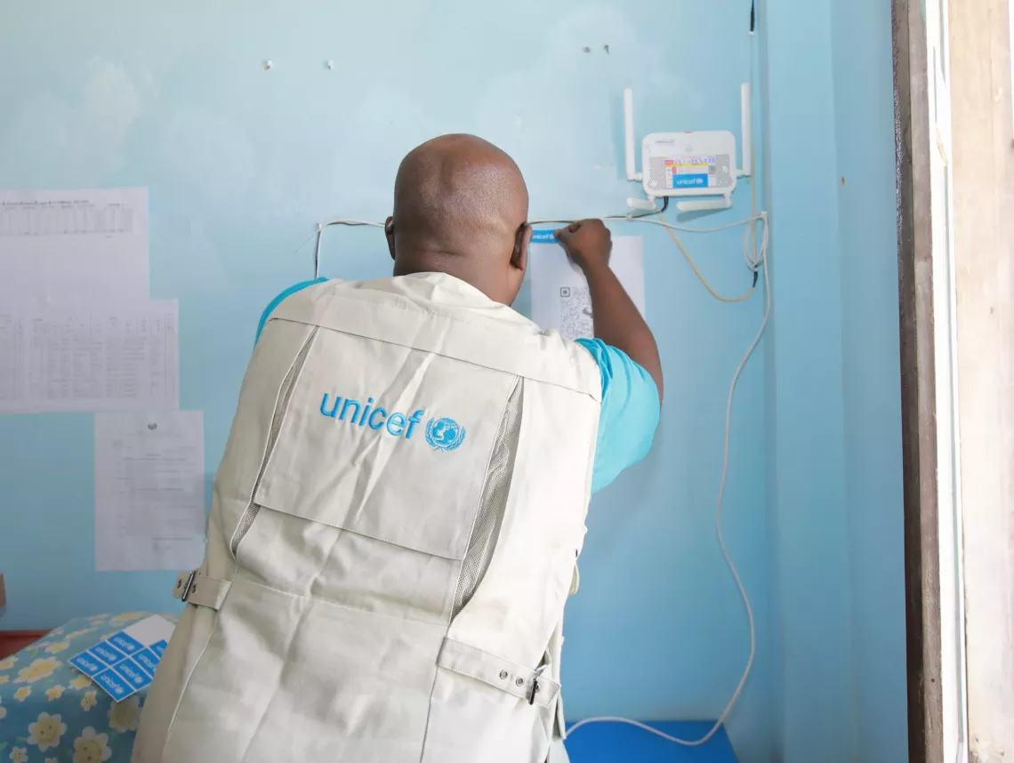 A UNICEF staff helps to install air quality monitoring sensors at the school.