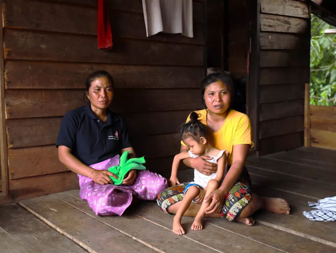 The mother from the first household with her child sharing her story with a village health volunteer.