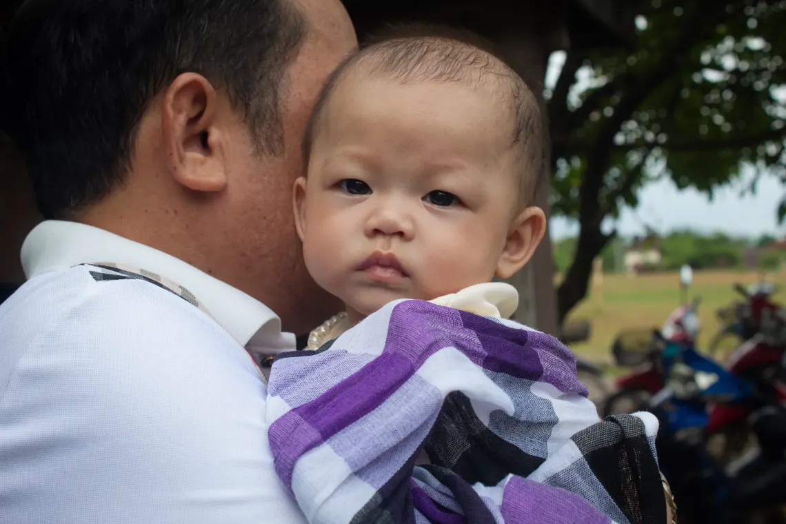 A father holds his baby close during a community parenting session in Lao PDR.