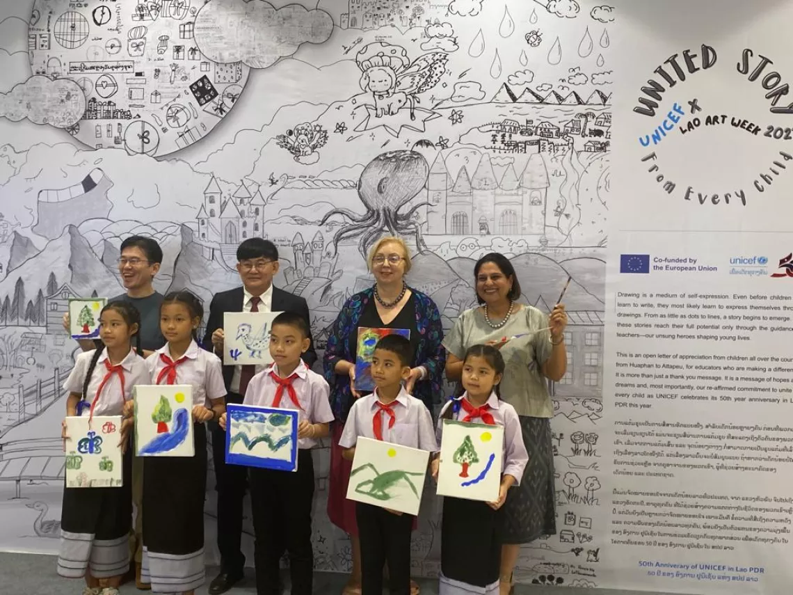 (Left to right) The Japanese Ambassador, Minister of Education and Sports, EU Ambassador and UNICEF Representative pose with children in front of the artwork entitled "A United Story from Every Child".